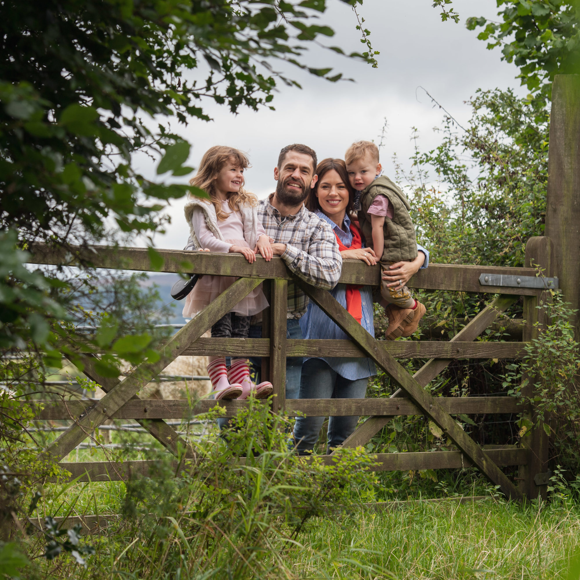 Farmer and family lean on farm gate