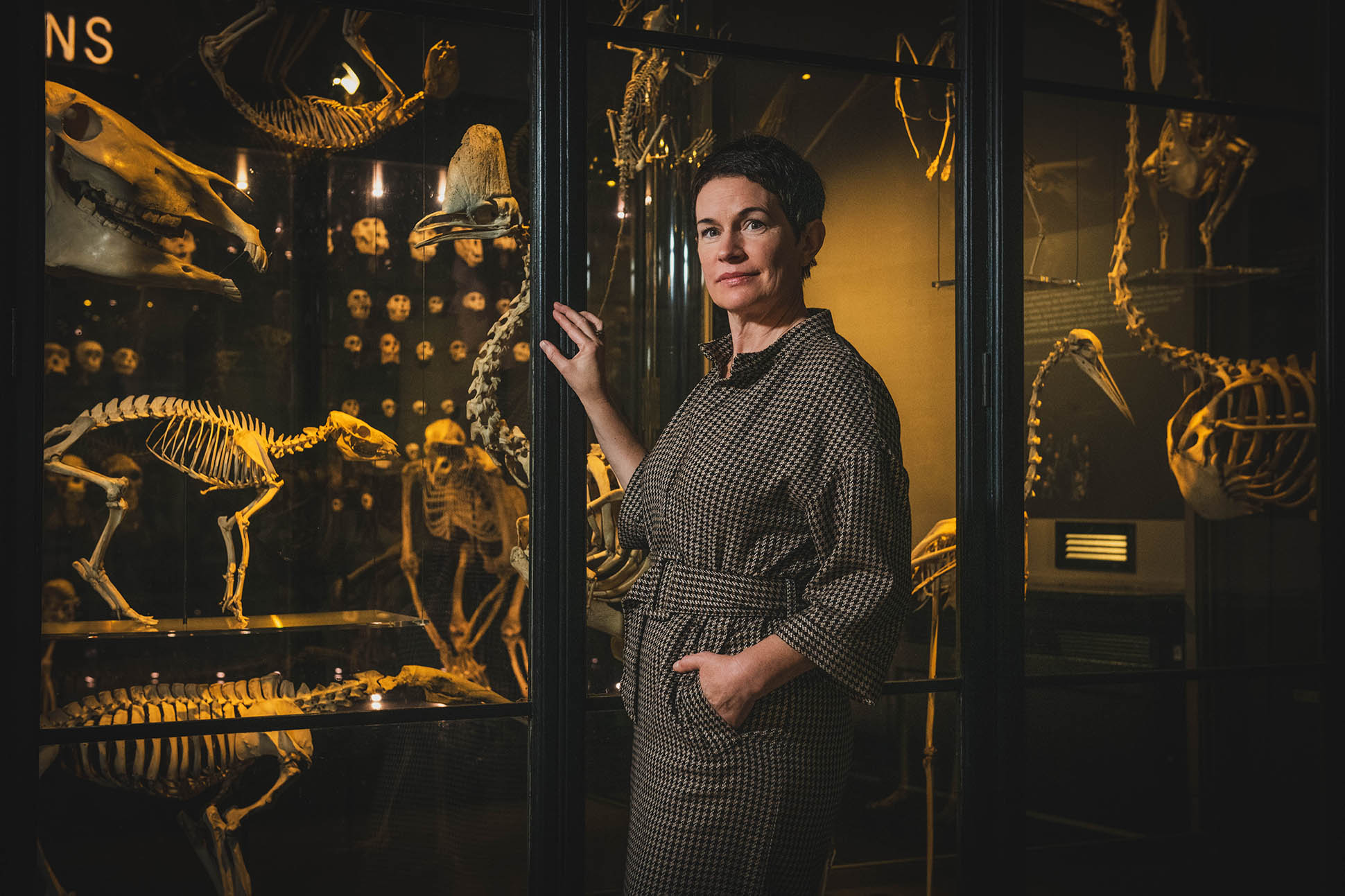 A female writer poses with skeletons on display at Manchester Museum.